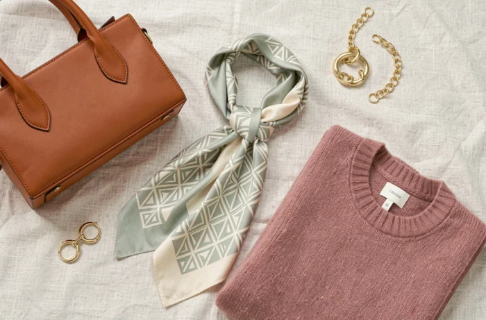 Flat lay d'accessoires et vêtements tendance 2024 soigneusement disposés sur fond en lin dans un studio mode